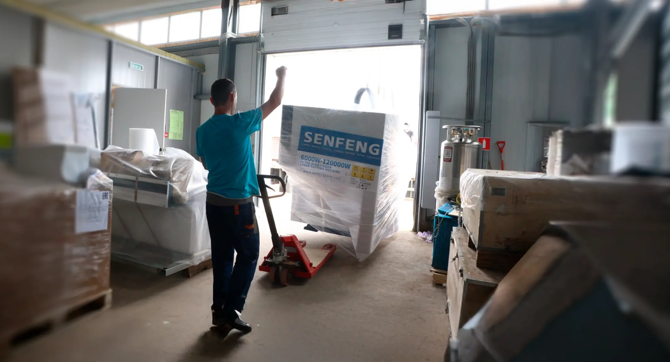 Empleado de Senfeng moviendo maquinaria embalada con una transpaleta.
